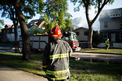 ANDREW RYAN / WINNIPEG FREE PRESS A Winnipeg firefighter looks onto the smouldering wreckage that has been left of a home on Manitoba Ave. that caught fire early morning in the city's North End on August 21, 2018.