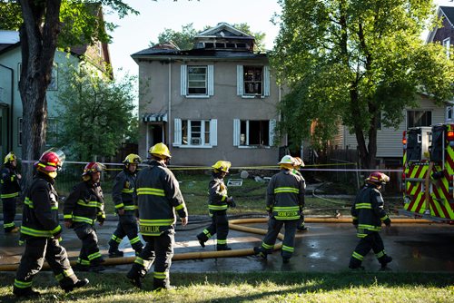 ANDREW RYAN / WINNIPEG FREE PRESS Firefighters walk passed the wreckage that has been left of a home that caught fire early morning on Manitoba Ave. in the city's North End on Manitoba Ave. August 21, 2018.