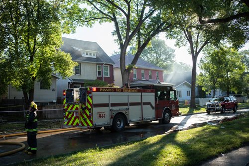 ANDREW RYAN / WINNIPEG FREE PRESS A Winnipeg firefighter looks onto the smouldering wreckage that has been left of a home on Manitoba Ave. that caught fire early morning in the city's North End on August 21, 2018.