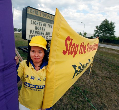 PHIL HOSSACK / WINNIPEG FREE PRESS -  Falun Dafa member Phuong Nguyen peers out from between protest banners at the entrance to the Chinese Northern Lights exhibition Friday. See Carol Sanders story.  - August 31, 2018