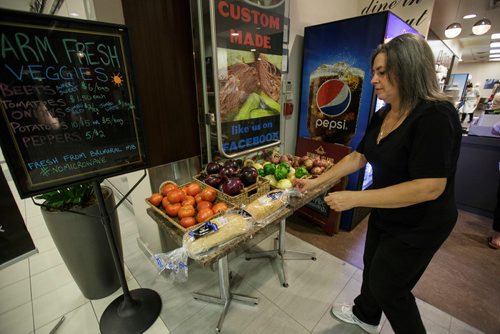 MIKE DEAL / WINNIPEG FREE PRESS
Nathan Detroit's Lunch Pad, 1 Lombard Place (directly beneath the Richardson Bldg/Fairmont Hotel) 
Brenlea Yamron tidies up the table with farm veggies from Balmoral, Manitoba, which they sell to customers.
180906 - Thursday, September 06, 2018.