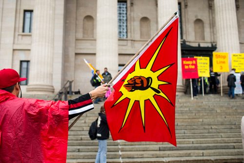 MIKAELA MACKENZIE / WINNIPEG FREE PRESS
Shaun Laquette holds a flag at a rally calling for a clean energy future in front of the Manitoba Legislative Building  in Winnipeg on Saturday, Sept. 8, 2018. 
Winnipeg Free Press 2018.