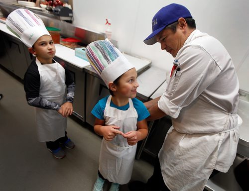 PHIL HOSSACK / WINNIPEG FREE PRESS - STAND-UP - Chef Wayne Martin wrangles 7 yr old Jaerden Peters (centre) works her apron while her brother Jaerden (8) watches Monday evening at his new resteraunt the "Capitol Grill on Broadway" during a Variety Children's Charity of Manitoba event for about 60 special needs kids and their parents. See release and Doug's story.   - Sept 24, 2018