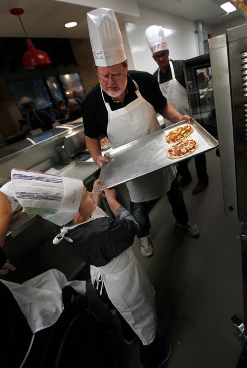 PHIL HOSSACK / WINNIPEG FREE PRESS - Doug Speirs and 8 yr old Jaerden Peters wrangle a pair of pizza's into the oven Monday evening at Capitol Grill on Broadway resteraunt during a Variety Children's CHarity of Manitoba event for about 60 special needs kids and their parents. See release and Doug's story.   - Sept 24, 2018