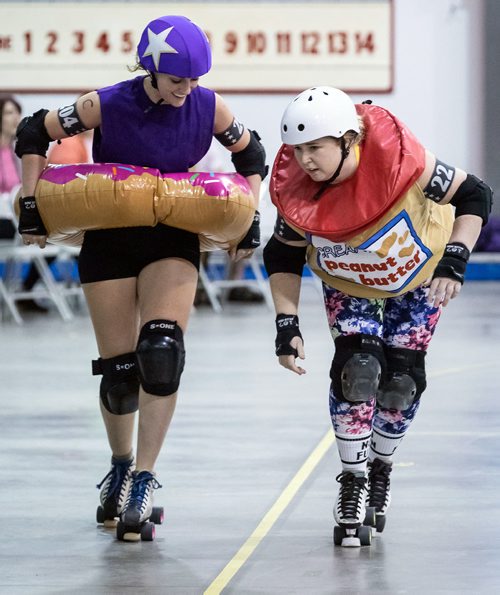 SUBMITTED PHOTO / MATT DUBOFF

Skaters Alex 'The Grape Gatsby' Krosney (left) and Victoria 'Scone Cold B*tch' Currie face off as a doughnut and a jar of peanut butter in the Winnipeg Roller Derby League's FUNraiser game in support of the North Point Douglas Women's Centre on Sept. 7, 2018. (See Social Page)
