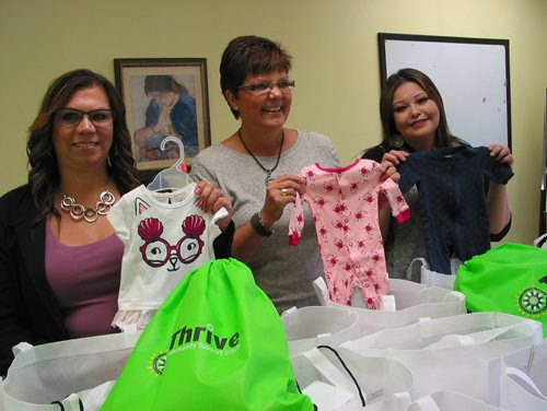 Canstar Community News Oct. 2, 2018 - (From left) Thrive Community Support Circle executive director Rhonda Elias-Penner and program Manager Dakotah Nadeau (at right) look at the baby clotes in the 50 layettes that Headingley's Sherry Desilets, Nighty Noodles organizer, dropped off on Oct. 2. (ANDREA GEARY/CANSTAR COMMUNITY NEWS)