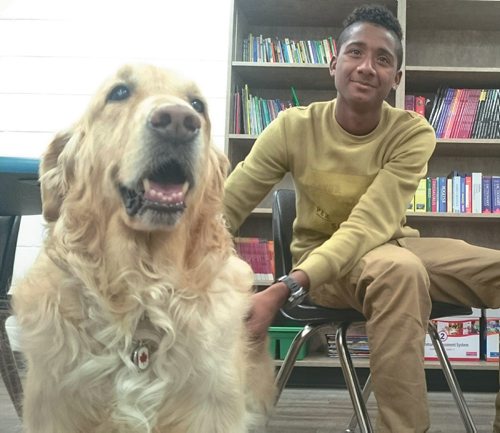Canstar Community News Kennay the EAL dog at Miles Macdonnell Collegiate poses for a photo with student Miguel Selinas.