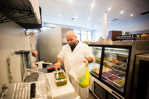 MIKAELA MACKENZIE / WINNIPEG FREE PRESS
Murhaf Abdul Karim spoons olives into the display case as Blady Middle Eastern market opens in Winnipeg on Friday, Oct. 26, 2018. 
Winnipeg Free Press 2018.