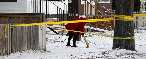 PHIL HOSSACK / WINNIPEG FREE PRESS - A woman sweeps snow from her walkway past a web of police tape two doors down from 335 Bannerman where a gunaman held police at bay Wednesday. - November 8, 2018