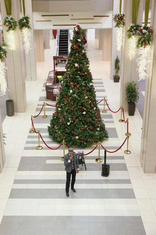 MIKE DEAL / WINNIPEG FREE PRESS
Chad Celaire, in front of the huge tree in Cityplace shopping centre, has for the last three holiday seasons rented out his vocal services, billing himself as The Christmas Singer. 
181127 - Tuesday, November 27, 2018.