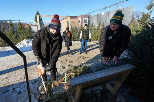DAVID LIPNOWSKI / WINNIPEG FREE PRESS

Miles Macdonell Collegiate Buckeyes Receiver Miciah Stone (left) and Offensive Lineman Matthew Stow (right), help cut a Christmas tree to size for Amber Johnston (second from left) and roommate Jay Harasymchuk (second from right) at the non-profit volunteer operated Tree Lot at 454 Kimberly Avenue beside Miles Macdonell Collegiate Saturday December 8, 2018.