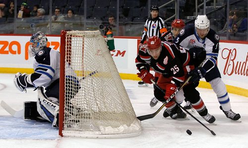PHIL HOSSACK / WINNIPEG FREE PRESS - Grand Rapids Griffins' #25 Chris Terry works around the Manitoba Moose net with Moose #5 Cameron Schilling on his back. Griffins #19 Carter Camper following up. December 21, 2018.