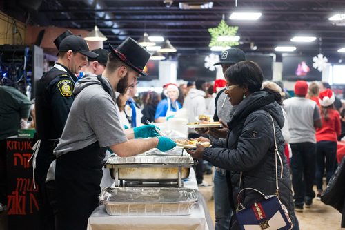 MIKAELA MACKENZIE / WINNIPEG FREE PRESS
Maggie Yeboah is served by Nello DeStefano at the 13th Annual Christmas Eve Feast for new immigrants, international students who cant make it home for the holidays, and people in the inner city at X-Cues Café in Winnipeg on Monday, Dec. 24, 2018. 
Winnipeg Free Press 2018.