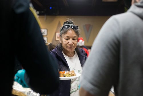 MIKAELA MACKENZIE / WINNIPEG FREE PRESS
Marcy Hobson is served a the 13th Annual Christmas Eve Feast for new immigrants, international students who cant make it home for the holidays, and people in the inner city at X-Cues Café in Winnipeg on Monday, Dec. 24, 2018. 
Winnipeg Free Press 2018.