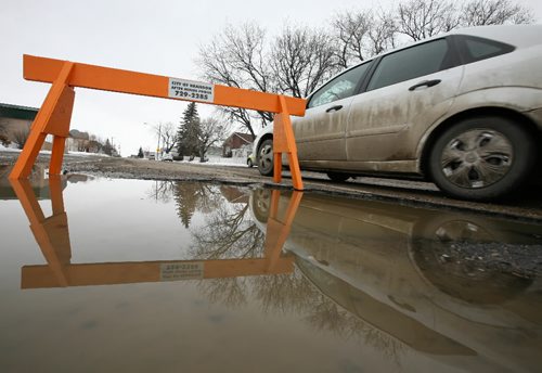 Brandon Sun 03042009 A vehicle passes a large water-filled pothole on 9th St. between College Ave. and Park Ave. in Brandon on Friday afternoon. The extreme weather that Brandon as felt throughout this winter has worn heavily on the cities roads. (Tim Smith/Brandon Sun)