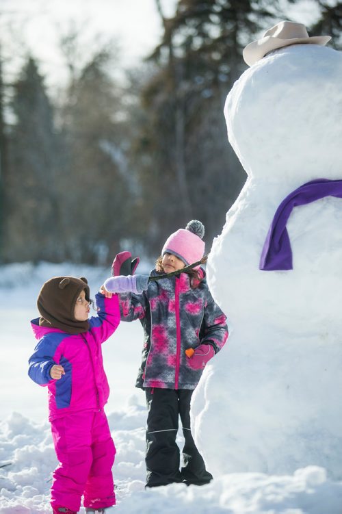 MIKAELA MACKENZIE / WINNIPEG FREE PRESS
Gabrielle (three) and Amelia (five) Happychuk try to high five the snowman they made with their dad at St. Vital Park in Winnipeg on Thursday, Jan. 3, 2019. 
Winnipeg Free Press 2018.