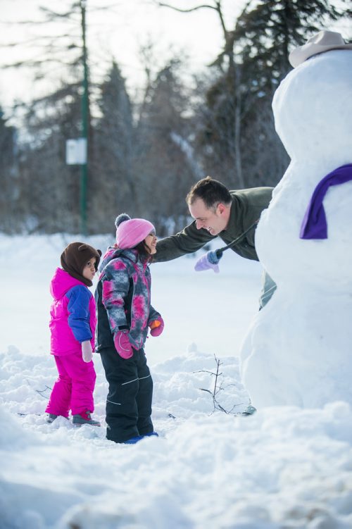 MIKAELA MACKENZIE / WINNIPEG FREE PRESS
Brock Happychuk tries to take a picture of his daughters, Gabrielle (three) and Amelia (five), with the snowman they built while his other daughter,  runs around at St. Vital Park in Winnipeg on Thursday, Jan. 3, 2019. 
Winnipeg Free Press 2018.