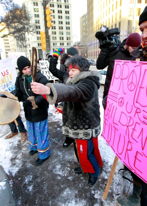 PHIL HOSSACK / WINNIPEG FREE PRESS - Protest organizer Alma Kakikepinace raises her eagle feather as she speaks to the rally at Portage and Main Thursday. See Kevin Rollason's story. January 10, 2019