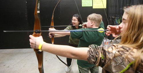 JOHN WOODS / WINNIPEG FREE PRESS
Diane Minion, with Heights Archery Range, shows nine year old Madden Touchette and Kymber Dyck how to shoot a bow and arrow during the Manitoba Outdoors Show at Red River Exhibition Place in Winnipeg Sunday, February 10, 2019.