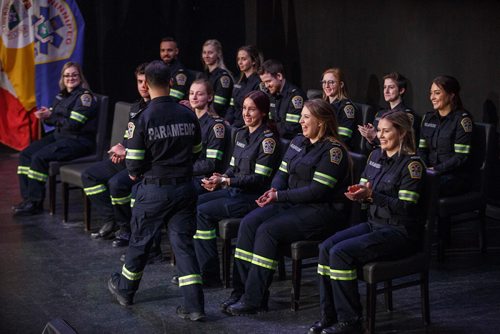 MIKE DEAL / WINNIPEG FREE PRESS
Classmates laugh and clap as Josh Sanchez walks back to his seat after receiving his badge and registration number during a graduation ceremony at The Metropolitan Entertainment Center Friday morning. Fourteen Primary Care Paramedic (PCP) recruits graduate from Winnipeg Fire Paramedic Services six-week orientation and training class during a ceremony Friday morning at The Metropolitan Entertainment Center.
190301 - Friday, March 01, 2019.