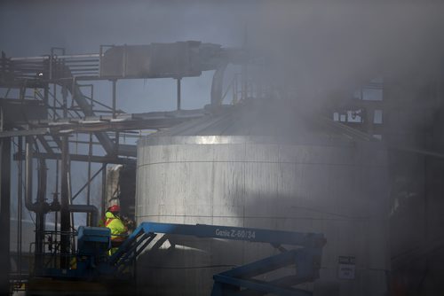 TREVOR HAGAN / WINNIPEG FREE PRESS
Seen through exhaust, workers install new insulation on a silo after a fire on the 600 block of Dawson Street North, Saturday, March 2, 2019.
