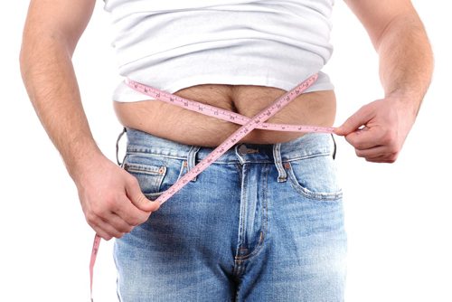 Canstar Community News Man fat belly in jeans.  Overweight man with tape measure around waist