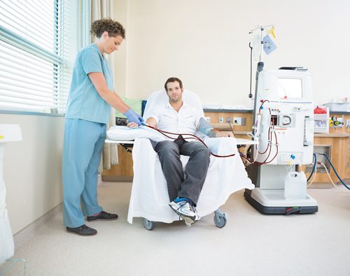 Canstar Community News Portrait of male patient being prepared by nurse before renal dialysis in hospital room