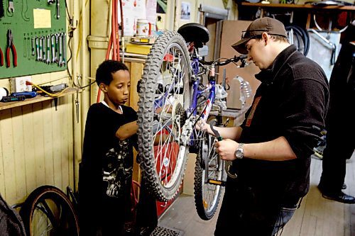 BORIS MINKEVICH / WINNIPEG FREE PRESS  090430 Bike Dump. Volunteer Tyler Markowsky helps 13 year old Thomas Habte fix his bike.