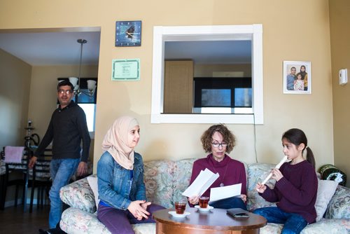 MIKAELA MACKENZIE / WINNIPEG FREE PRESS
Alana Langelotz helps the girls, Shahed (left) and Ghena Humsi, read their report cards as their dad, Yasser Humsi, walks past at the Humsi family home in Winnipeg on Tuesday, March 12, 2019. The two families met through a Volunteer Matching Program with the Manitoba Interfaith Immigration Council that pairs Canadians up with newcomers.
Winnipeg Free Press 2019.