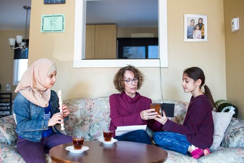 MIKAELA MACKENZIE / WINNIPEG FREE PRESS
Alana Langelotz helps the girls, Shahed (left) and Ghena Humsi, read their report cards at the Humsi family home in Winnipeg on Tuesday, March 12, 2019. The two families met through a Volunteer Matching Program with the Manitoba Interfaith Immigration Council that pairs Canadians up with newcomers.
Winnipeg Free Press 2019.