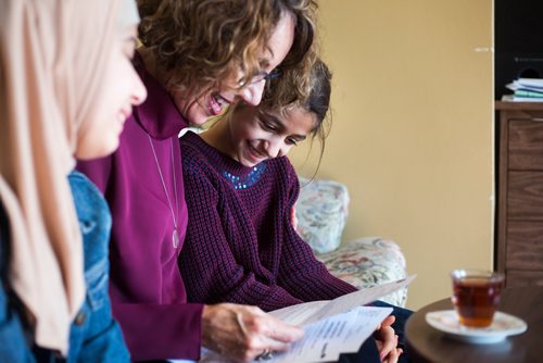 MIKAELA MACKENZIE / WINNIPEG FREE PRESS
Alana Langelotz helps the girls, Shahed (left) and Ghena Humsi, read their report cards at the Humsi family home in Winnipeg on Tuesday, March 12, 2019. The two families met through a Volunteer Matching Program with the Manitoba Interfaith Immigration Council that pairs Canadians up with newcomers.
Winnipeg Free Press 2019.