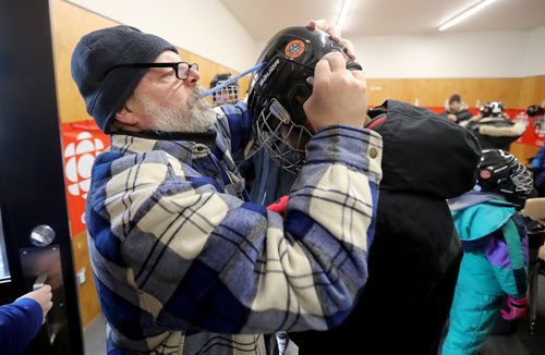 TREVOR HAGAN / WINNIPEG FREE PRESS
Randy Turner taking a moment away from work to help someone put on a hockey helmet during True North Foundation activities at Camp Manitou, Sunday, February 4, 2018.