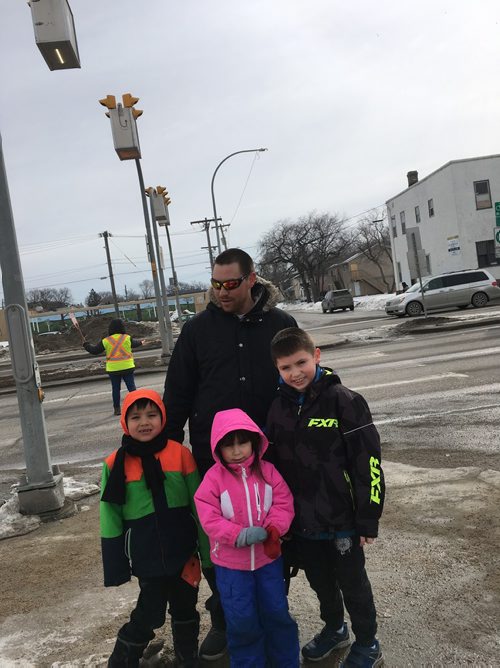 Parent Shane Connolly  with his kids (from left) - Colten, Xzandra, and Wyatt at lunch time by Dufferin School Tuesday to cross busy Isabel Street with them, even though there is a crossing guard on duty. Connolly said that flashing warning lights ahead of the pedestrian crosswalk might make is safer. 
CAROL SANDERS / WINNIPEG FREE PRESS