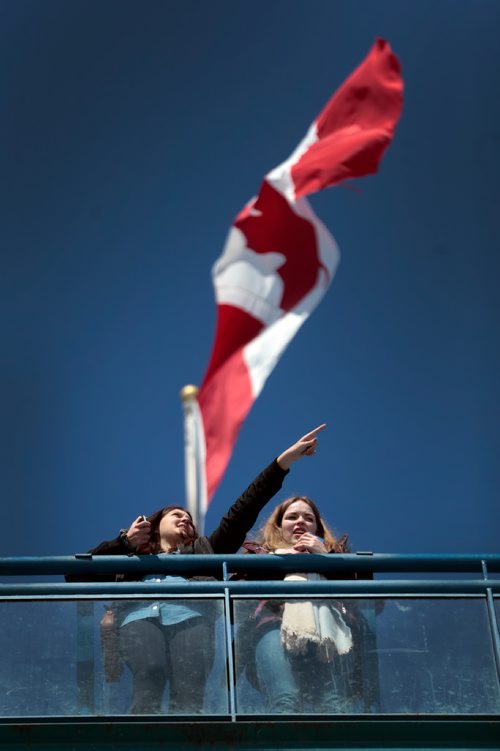 PHIL HOSSACK / WINNIPEG FREE PRESS  - Clear cloudless skies and a spring breezes fluttering the flag above Kaila Reimer (left) as she points out the sights from the observation tower at the Forks to her friend Lea Hartmann. The pair met a few years ago as exchange students, Lea is from Germany visiting Winnipeg in Spring. -  March 20, 2019.