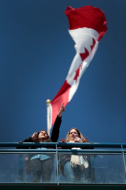 PHIL HOSSACK / WINNIPEG FREE PRESS  - Clear cloudless skies and a spring breezes fluttering the flag above Kaila Reimer (left) as she points out the sights from the observation tower at the Forks to her friend Lea Hartmann. The pair met a few years ago as exchange students, Lea is from Germany visiting Winnipeg in Spring. -  March 20, 2019.