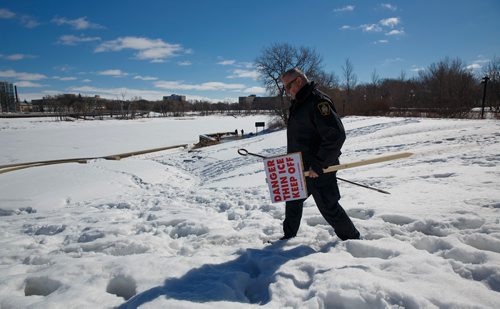 MIKE DEAL / WINNIPEG FREE PRESS
Winnipeg Police Service Constable Ray Duma with a warning sign alerting people to the danger of thin ice on the Red River at The Forks. He and his colleagues have been putting up the signs along the Red and Assiniboine Rivers the last couple days as the weather has warmed up significantly. 
190320 - Wednesday, March 20, 2019.