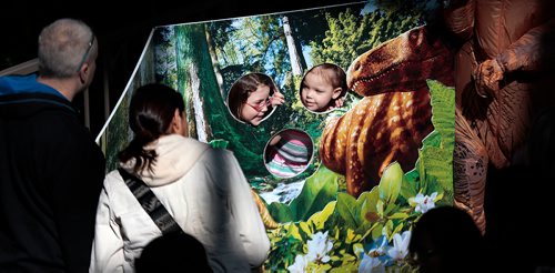 PHIL HOSSACK / WINNIPEG FREE PRESS - Shealyn Peters-St. Paul (6yrs) and her sister Taya (3) (right) peek out of a dinosaur backdrop Saturday afternoon at the Royal Canadian Mint's Dinosaur Day. The vent drew capacity crowds all day. See Release STAND-UP.   - March 30, 2019.