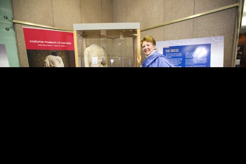 MIKAELA MACKENZIE / WINNIPEG FREE PRESS
Margaret Mills, board member of the Costume Museum, poses for a portrait with the Muriel Richardson dress on display in the Richardson Building in Winnipeg on Monday, April 1, 2019.  For Cassidy Dankochik story.
Winnipeg Free Press 2019.