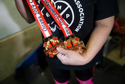 MIKE DEAL / WINNIPEG FREE PRESS
Susan Haywood a record-breaking 70-year-old power lifter with her Nationals medals in her home gym near Teulon, Manitoba.
190403 - Wednesday, April 03, 2019.