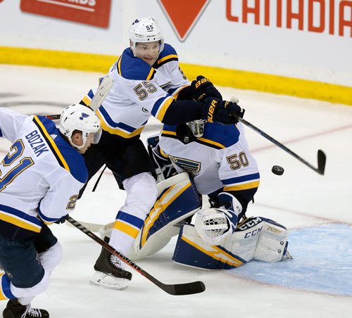 PHIL HOSSACK / WINNIPEG FREE PRESS - St Louis Blues # 55 Colton Parakayo swings at a flying puck in the crease of #50 Jordan Binnington, #21 Tyler Bozak watches in playoff action Friday. April 12, 2019