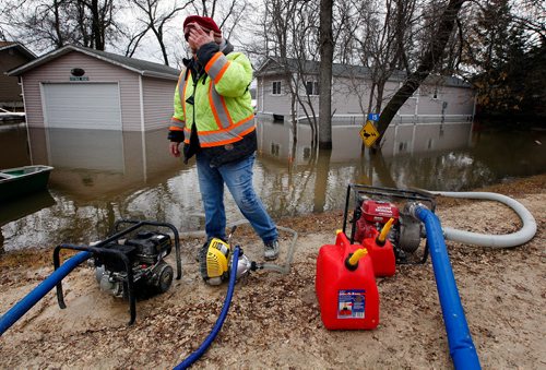 PHIL HOSSACK / WINNIPEG FREE PRESS -  Tanis Taylor mans the pumps behind her nephew Eddie Taylor's summer home along Netley Creek near Petersfield Monday afternoon. An ice  jam on the Red River sent creek levels up fast overnight, municipal officials placed tiger dykes and raised at least one road to protect most homes. Floodwaters breached the dike in front of the Taylor's property despite municipal efforts. April 15, 2019.