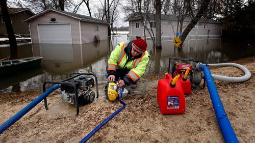 PHIL HOSSACK / WINNIPEG FREE PRESS -  Tanis Taylor mans the pumps in front of her Nephew Eddie Taylor's summer home along Netley Creek near Petersfield Monday afternoon. An ice  jam on the Red River sent creek levels up fast overnight, municipal officials placed tiger dykes and raised at least one road to protect most homes. Floodwaters breached the dike in front of the Taylor's property despite municipal efforts. April 15, 2019.