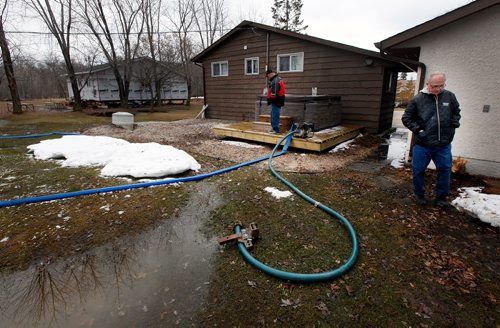 PHIL HOSSACK / WINNIPEG FREE PRESS -  Tim (right) and brother Danny (left) Martel survey Tim's Petersfield area back yard after floodwaters breached a dike behind his home Sunday night sending floodwaters into his yard and up to the house he purchased a year ago. An ice  jam on the Red River sent creek levels up fast overnight, municipal officials placed tiger dykes and raised at least one road to protect most homes. Floodwaters breached the dike behind Martel's property despite municipal efforts. April 15, 2019.