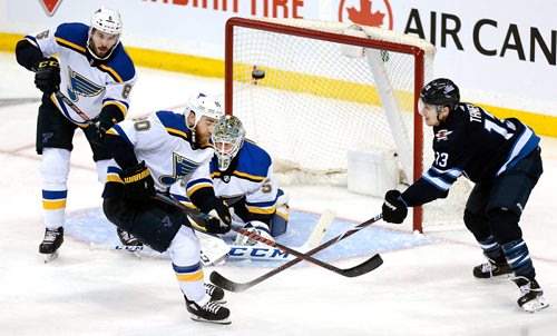 PHIL HOSSACK / WINNIPEG FREE PRESS -St Louis Blues #6 Joel Edmundson clears the puck into the crowd in front of net minder Jordan Binnington and #90 Ryan O'Reilly in the 3rd period Thursday in Winnipeg. Edmundson took a 2 minute minor for delaying the game. - April 18, 2019.