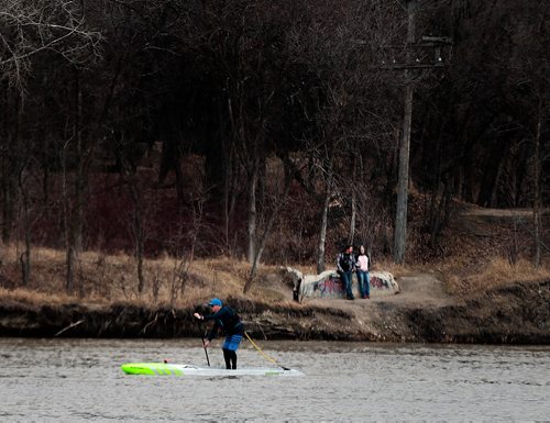 PHIL HOSSACK / WINNIPEG FREE PRESS - The early paddler gets...the current, Strong spring currents across from Kildonan Park push a spring paddle boarder north towards the Bergen Cutoff Railway Bridge Friday afternoon as temperatures soared up to near 20C with a forecast of rain tomorrow and Sun on Sunday. - April 19, 2019.