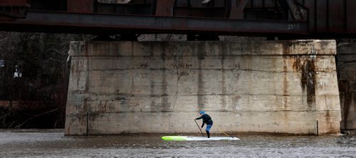 PHIL HOSSACK / WINNIPEG FREE PRESS - The early paddler gets...the current, Strong spring currents push a spring paddle boarder north as he slips under the Bergen Cutoff Railway Bridge Friday afternoon as temperatures soared up to near 20C with a forecast of rain tomorrow and Sun on Sunday. - April 19, 2019.