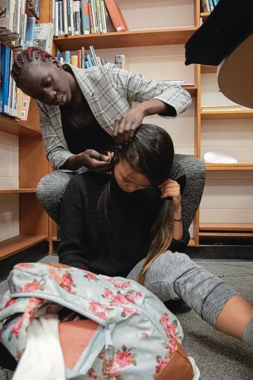 Canstar Community News Ashla Deing braids Kristine Navea hair during the Peaceful Village program at St. James Collegiate and George Waters Middle School. (EVA WASNEY/CANSTAR COMMUNITY NEWS/METRO)