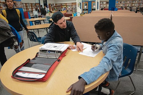 Canstar Community News Staff member Michael Roberts helps Grade 10 student Deing Deing with biology homework during a Peaceful Village drop-in at St. James Collegiate and George Waters Middle School.(EVA WASNEY/CANSTAR COMMUNITY NEWS/METRO)