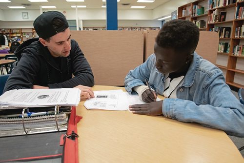 Canstar Community News Staff member Michael Roberts helps Grade 10 student Deing Deing with biology homework during a Peaceful Village drop-in at St. James Collegiate and George Waters Middle School.(EVA WASNEY/CANSTAR COMMUNITY NEWS/METRO)