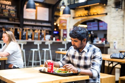 MIKAELA MACKENZIE / WINNIPEG FREE PRESS
Jude Asainayagam enjoys a cheeseburger on a ceramic plate at The Forks in Winnipeg on Tuesday, June 11, 2019.  The Forks recently replaced dishware with 100% reusable and compostable products in its path towards a zero-waste goal. For Tessa Vanderhart story.  
Winnipeg Free Press 2019.